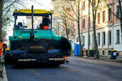 Eine große Asphaltbaumaschine (Straßenfertiger) bei der präzisen Verlegung einer neuen Straßendecke in Leipzig – professionelle Industriefotografie für das Bauwesen.